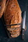 Pane rustico fatto in casa parzialmente affettato su tavola di legno — Foto stock