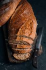Pane rustico fatto in casa parzialmente affettato su tavola di legno — Foto stock