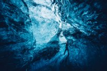 View of traveler walking in crack of beautiful crystal blue ice cave, Iceland — Stock Photo