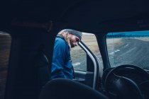 Чоловік сидить всередині автомобіля на водійському сидінні під час подорожі через Ісландію. — стокове фото