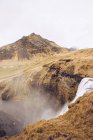 Rio de montanha com cascata de água entre colinas de pedra marrom e vista sobre? planície na Islândia — Fotografia de Stock
