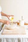 Cortado de mulher derramando manteiga em tigela na cozinha . — Fotografia de Stock