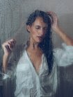 Sopping mujer en camisa posando en cabina de ducha - foto de stock