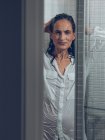 Sopping femme en chemise avec les mains dans les cheveux posant dans la douche — Photo de stock