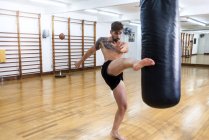 Kickboxing fighter training in gym with punch bag — Stock Photo