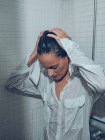 Jeune femme humide en chemise debout dans la douche — Photo de stock