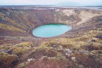De cima lago na cratera entre a morte terras marrons e colinas com céu? em nuvens na Islândia — Fotografia de Stock
