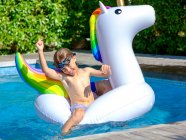 Garçon nageant sur flotteur licorne — Photo de stock