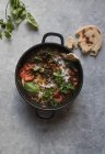 Olla de ragú con lentejas y curry de batata en la mesa gris - foto de stock