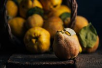 Quince fruit on dark wooden background with basket on background — Stock Photo