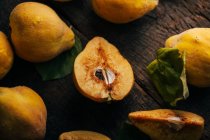 Mezze mele cotogne intere e fresche su fondo di legno scuro — Foto stock