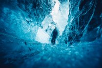 Человек в красивой голубой ледяной пещере — стоковое фото