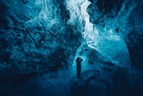 Hombre en hermosa cueva de hielo azul - foto de stock