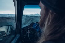 Вид сзади босоногого мужчины, управляющего автомобилем на холодной исландской террасе в сумерках — стоковое фото
