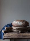 Fresh wholegrain bread loaf on rustic wooden table — Stock Photo