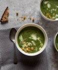 Ciotole con zuppa di spinaci, cavolo e crema di finocchio su superficie grigia — Foto stock