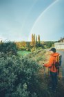 Hiker man on a trail in autumn colors with a double rainbow in the sky — Stock Photo