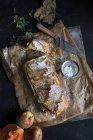 Домашняя тыква и яблочный штрудель на пергаменте с ингредиентами на тёмном фоне — стоковое фото