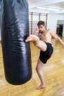Тренування винищувача кікбоксингу в спортзалі з мішком для ударів — стокове фото
