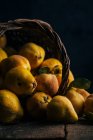 Fresh ripe quinces in upturned basket on dark wooden background — Stock Photo