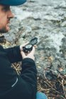 Молодой человек держит компас в горах рядом с рекой на коричневом фоне — стоковое фото