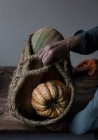 Hands of unrecognizable female holding basket with ripe pumpkins — Stock Photo