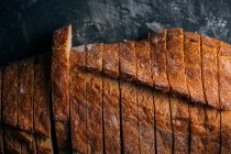 Slices of homemade rustic bread on dark background — Stock Photo