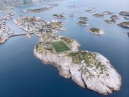 Drone view from height of Lofoten Islands with settlement and football field in blue ocean water, Norway — Stock Photo