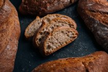 Домашній сільський хліб хліб хліб зі скибочками на темному фоні — стокове фото