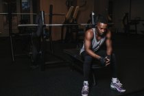 Schwarzer Mann mit Kopfhörern sitzt auf Trainingsgerät — Stockfoto