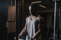 Black muscular man exercising in dark gym — Stock Photo