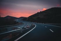 Highway in mountains at sundown with dramatic sky — Stock Photo