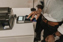 Von oben Handschuss eines afrikanisch-amerikanischen Mannes, der Tasten auf der Tastatur eines modernen Zahlungsterminals drückt — Stockfoto