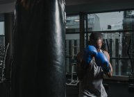 African American boxer training in dark gym — Stock Photo