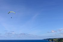 Magnifica vista drone di parapendio luminoso che vola contro cielo nuvoloso sopra bella natura verde nella giornata di sole — Foto stock