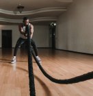 Negro chico ejercitando con cuerdas en gimnasio - foto de stock