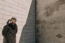 Uomo afroamericano in cappello di pelliccia appoggiato al muro di mattoni nella giornata di sole sulla strada della città — Foto stock
