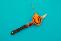 Sharp knife slicing tasty ripe tamarillo on bright blue background — Stock Photo