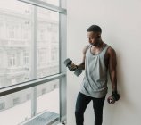 Homme noir avec haltères dans la salle de gym — Photo de stock