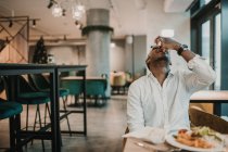 Adulto afro-americano homem desfrutando de deliciosa comida enquanto sentado à mesa em restaurante elegante — Fotografia de Stock