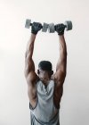 Черный мужчина с гантелями в спортзале — стоковое фото
