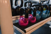 Modern kettle bells of various sizes lying on rack in modern gym — Stock Photo