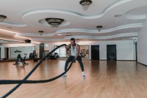 Noir guy exercice avec cordes dans salle de gym — Photo de stock