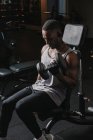 Чорний хлопець займається з гантелями в спортзалі — стокове фото