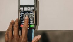 From above shot of hand of African American man pushing buttons on keypad of modern payment terminal — Stock Photo