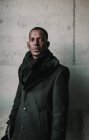 Bonito homem afro-americano em roupas quentes elegantes que estão perto da parede de concreto — Fotografia de Stock