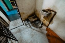 Small grungy sink attached to concrete wall near open door of dirty in prison in Oviedo, Spain — Stock Photo