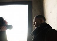 Hombre con cámara fotográfica profesional tomar fotos de hombre afroamericano con estilo cerca de la pared de hormigón - foto de stock