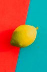 Fresh ripe lemon on bright red and blue background — Stock Photo