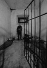 Homme flou méconnaissable debout près d'un mur de béton grogneux à l'intérieur d'une cellule de prison à Oviedo, Espagne — Photo de stock
